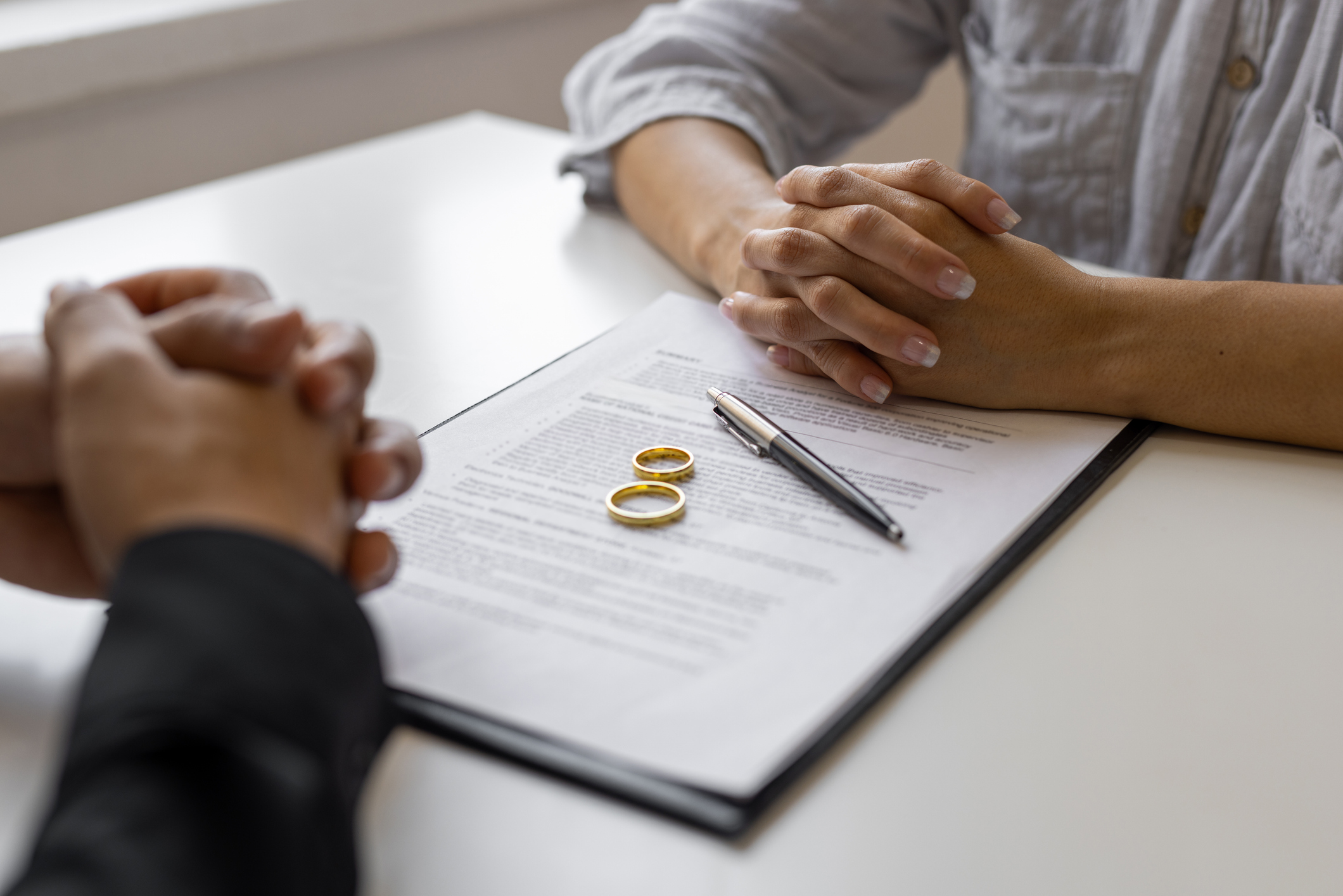 Person consulting with a divorce attorney, reviewing divorce documents with wedding rings